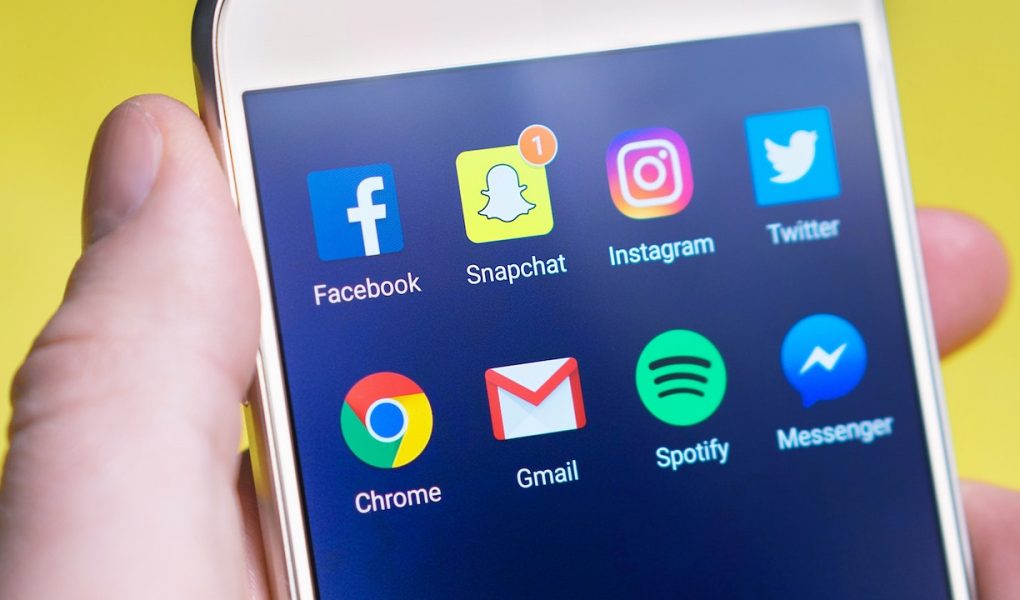 a hand holding a cellphone with social media buttons