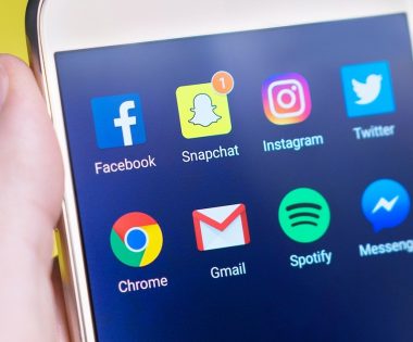 a hand holding a cellphone with social media buttons