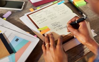 hands writing in a notebook - weekly planning for entrepreneurs