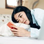 woman in bed looking at phone