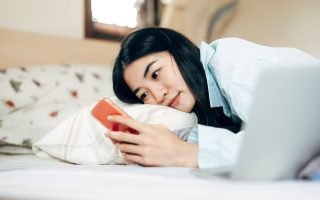 woman in bed looking at phone
