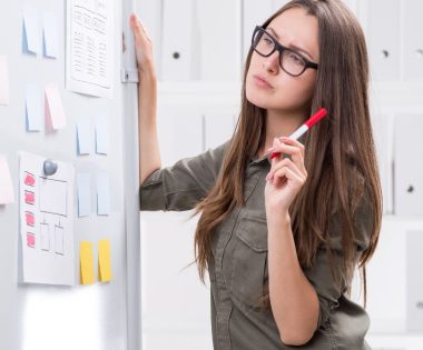 Woman writing on strategy board - Visibility strategy for women