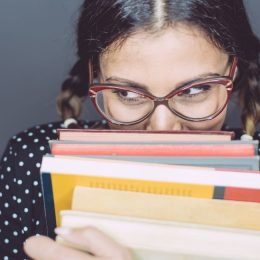 shy introvert woman hiding behind books